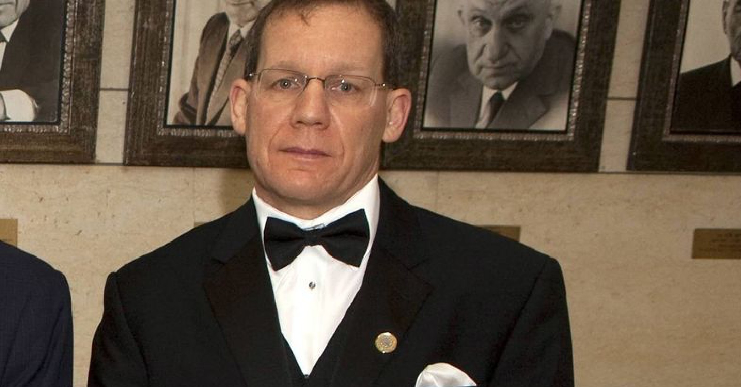 Man dressed in tuxedo, wearing glasses