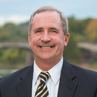 Header photo of Kevin Gowan, smiling for the photo wearing a dark-colored suit.